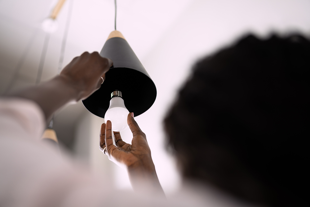 Woman installing an LED bulb in a light fixture.