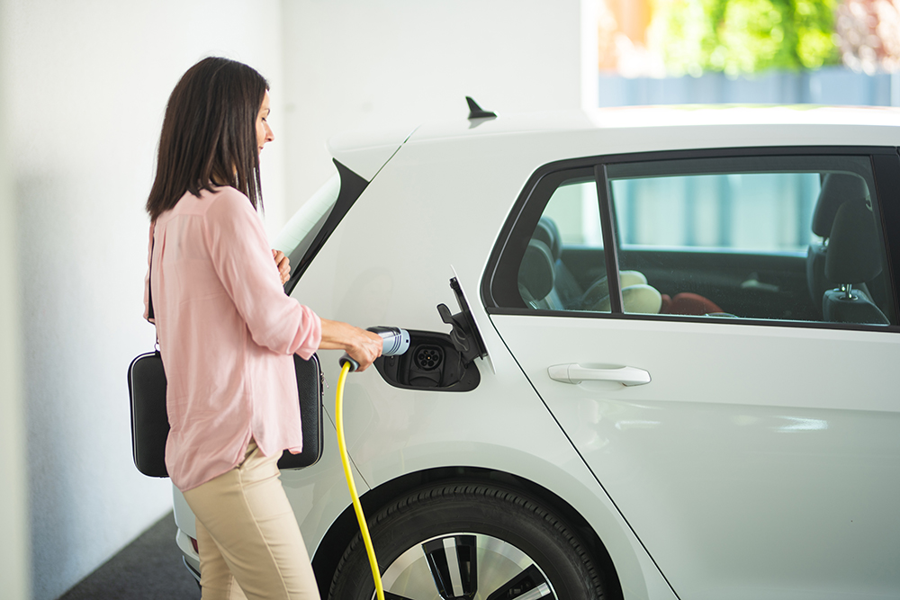 woman charging electric vehicle in her garage