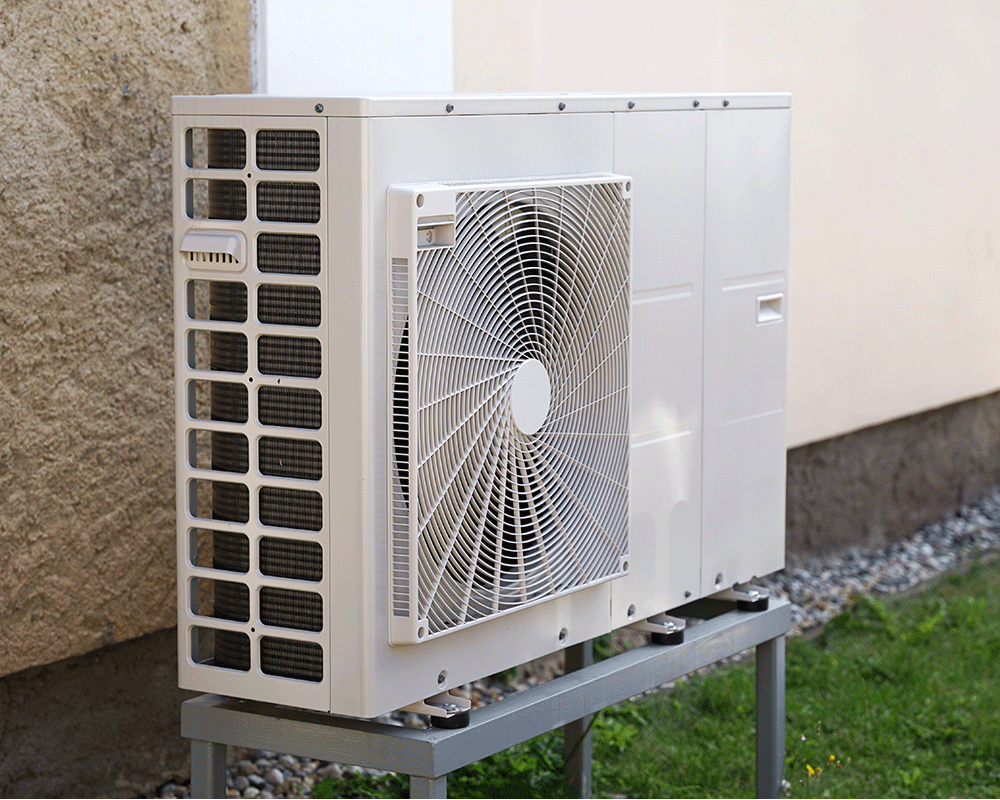 A closeup of a heat pump on the side of a home.